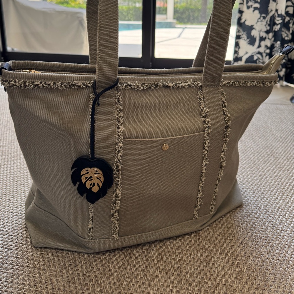 Tommy Bahama taupe canvas tote bag with top zipper and inside pockets.